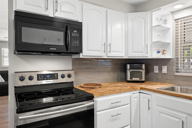 8766 91st St, Seminole, FL 33777 - kitchen featuring white cabinets, stainless steel range with electric cooktop, backsplash, black microwave, and wood counters