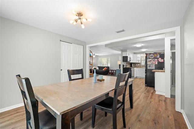 8766 91st St, Seminole, FL 33777 - dining area featuring light wood finished floors, baseboards, visible vents, and a notable chandelier