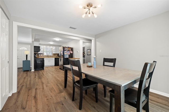 8766 91st St, Seminole, FL 33777 - dining room with baseboards, wood finished floors, visible vents, and a notable chandelier