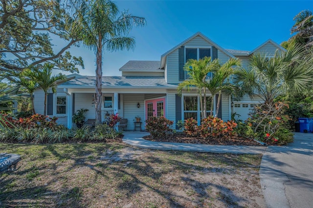 view of front of property featuring roof with shingles, covered porch, and a garage