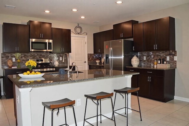 kitchen featuring light tile patterned floors, stainless steel appliances, and a breakfast bar area