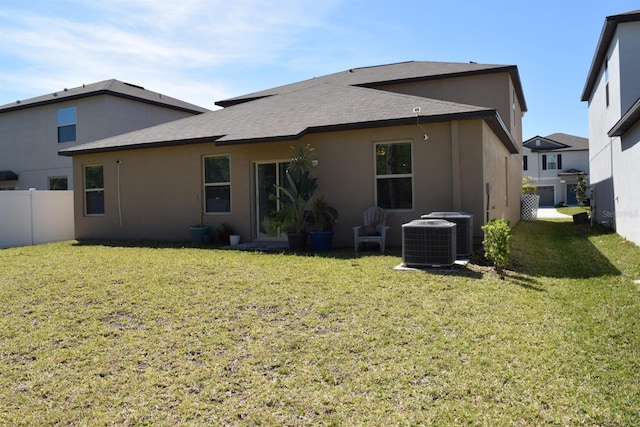 back of house with fence, a yard, and stucco siding
