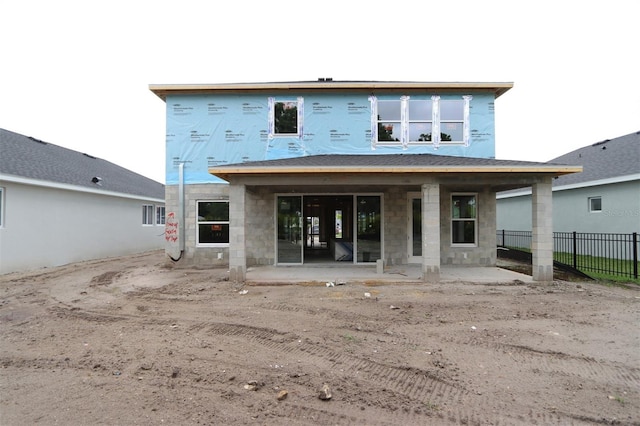 back of property featuring fence, concrete block siding, and a patio area