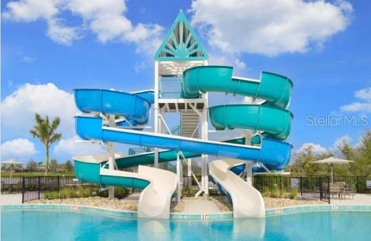 community pool featuring a water slide and fence