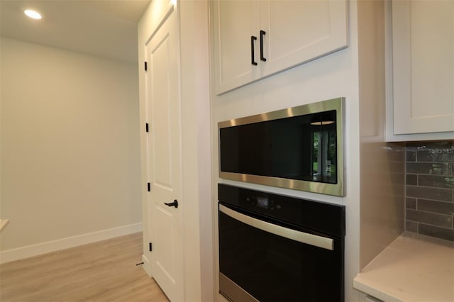 11884 Richmond Trl, Parrish, FL 34219 - kitchen with wall oven, stainless steel microwave, light wood-style flooring, white cabinets, and recessed lighting