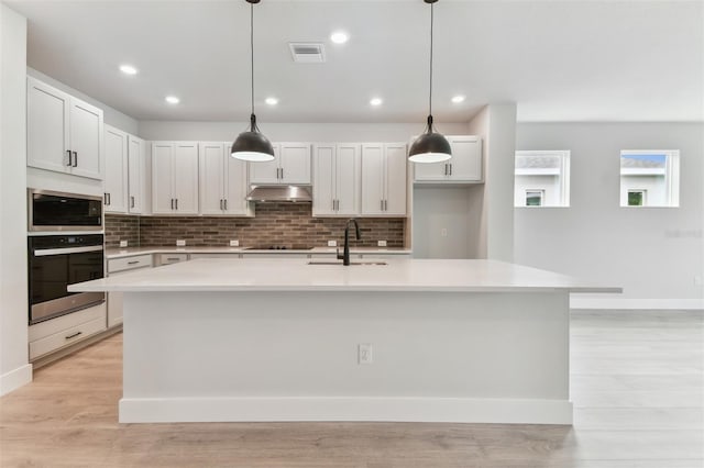 11884 Richmond Trl, Parrish, FL 34219 - kitchen with appliances with stainless steel finishes, under cabinet range hood, light countertops, decorative backsplash, and recessed lighting
