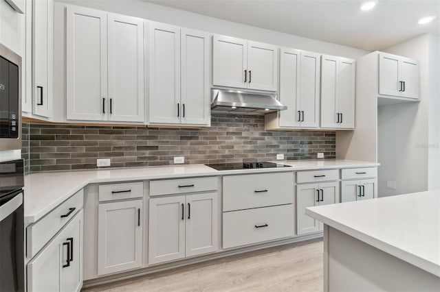 11884 Richmond Trl, Parrish, FL 34219 - kitchen with under cabinet range hood, black electric stovetop, light wood-style flooring, light countertops, and tasteful backsplash