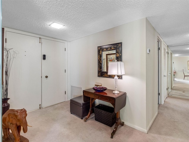 hallway with a textured ceiling, carpet, and visible vents