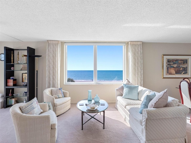 living area with carpet floors, a textured ceiling, and a water view