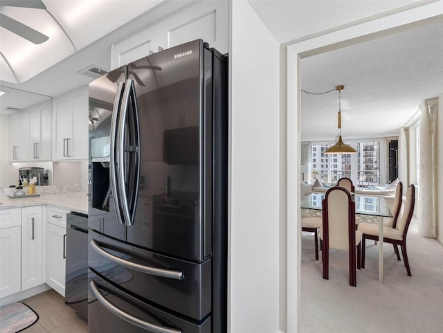 kitchen with stainless steel fridge, light carpet, decorative light fixtures, white cabinetry, and light stone countertops