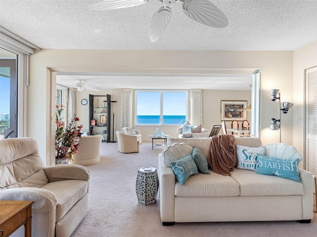 living area featuring carpet, a textured ceiling, and ceiling fan