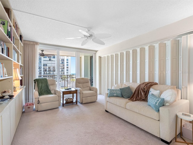 living room featuring light carpet, a ceiling fan, and a textured ceiling