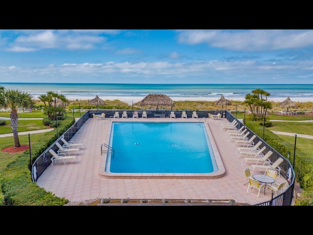pool with a view of the beach, a patio area, and a water view