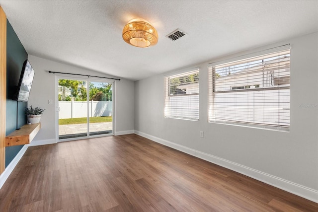 331 Barbara Cir, Belleair, FL 33756 - spare room featuring baseboards, wood finished floors, vaulted ceiling, and a textured ceiling