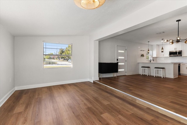 331 Barbara Cir, Belleair, FL 33756 - unfurnished living room featuring a chandelier, dark wood-style flooring, and baseboards