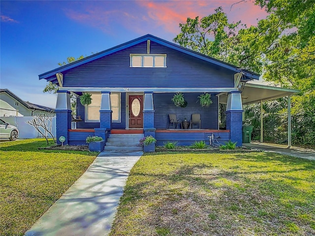 view of front of property with covered porch, a front yard, and a carport