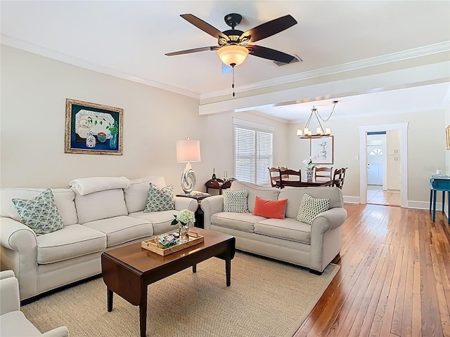 living area with light wood-style flooring, ornamental molding, ceiling fan with notable chandelier, and baseboards