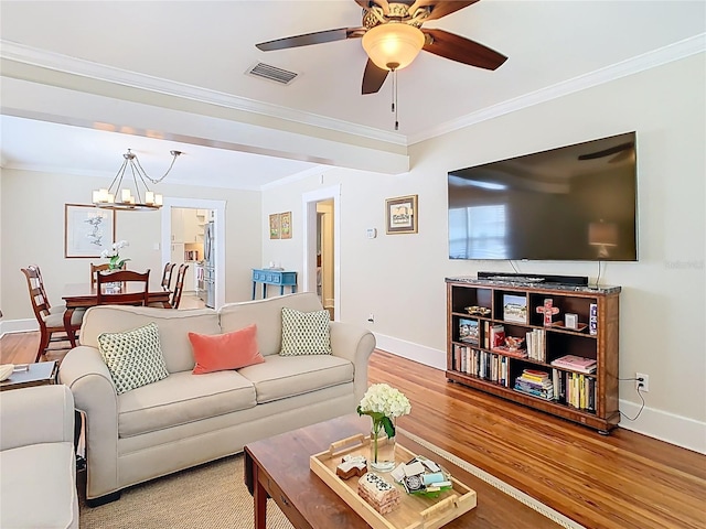 living area featuring visible vents, crown molding, baseboards, wood finished floors, and ceiling fan with notable chandelier