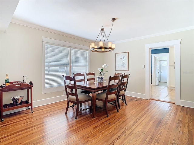 dining space with baseboards, ornamental molding, light wood-style floors, and a notable chandelier