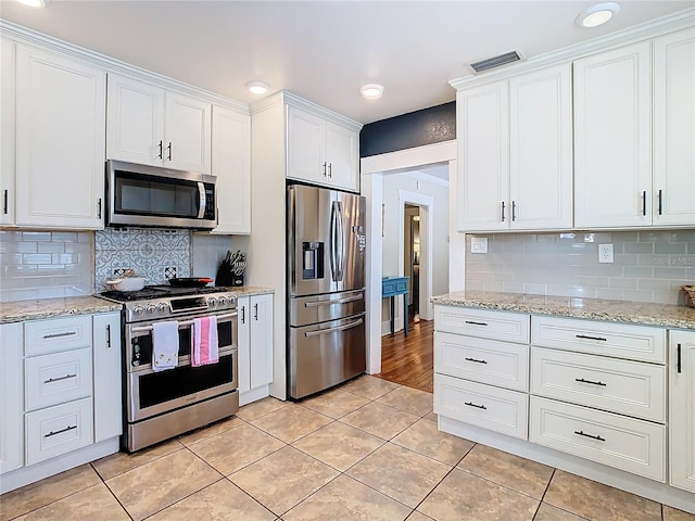 kitchen with white cabinetry, tasteful backsplash, light tile patterned flooring, visible vents, and appliances with stainless steel finishes