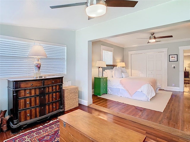 bedroom with baseboards, ceiling fan, wood finished floors, and a closet