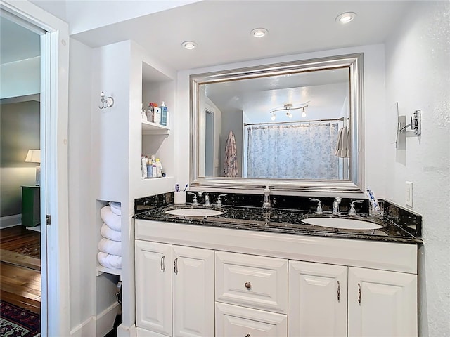 bathroom featuring double vanity, a sink, and recessed lighting