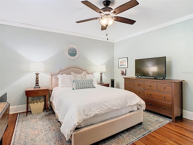 bedroom with baseboards, crown molding, wood finished floors, and a ceiling fan