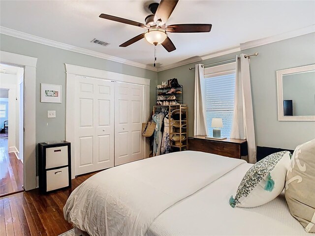 bedroom with crown molding, dark wood-style floors, multiple windows, visible vents, and a closet