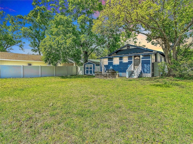 view of yard featuring a shed, entry steps, an outbuilding, and fence