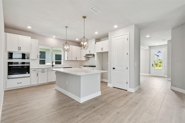 kitchen featuring stainless steel appliances, visible vents, backsplash, and white cabinetry