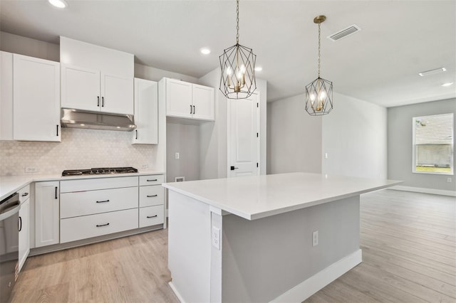 kitchen with under cabinet range hood, backsplash, visible vents, light wood-style flooring, and appliances with stainless steel finishes