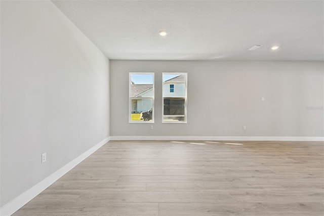 spare room featuring recessed lighting, light wood-type flooring, and baseboards