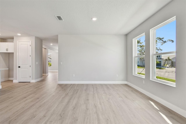 empty room featuring baseboards, light wood-style flooring, visible vents, and recessed lighting