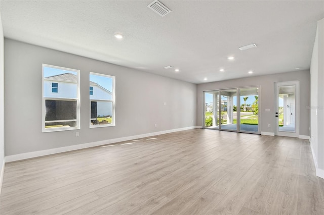 spare room featuring light wood finished floors, baseboards, visible vents, and recessed lighting