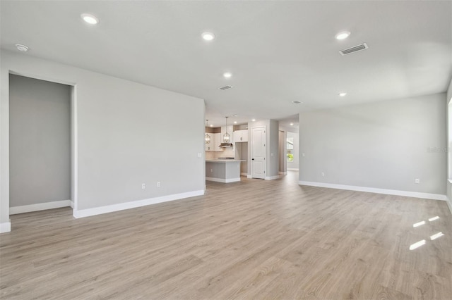 unfurnished living room with recessed lighting, light wood-style flooring, visible vents, and baseboards