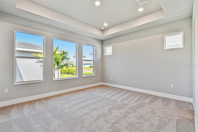 carpeted spare room featuring a tray ceiling, baseboards, and recessed lighting