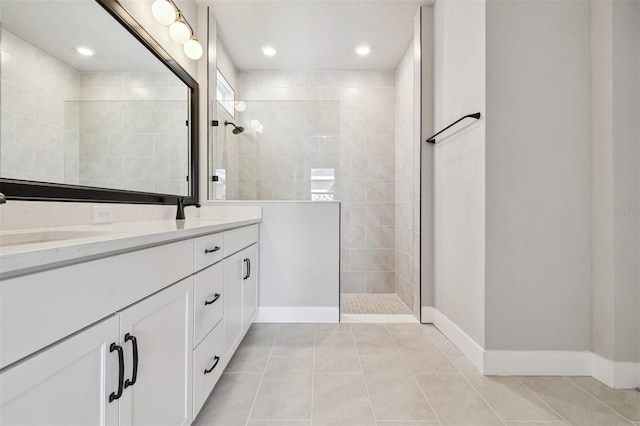 bathroom featuring tile patterned floors, double vanity, a sink, baseboards, and walk in shower