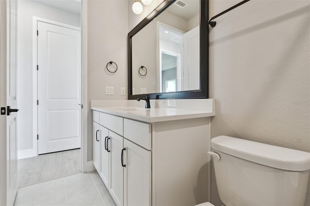 half bathroom with vanity, tile patterned flooring, and toilet