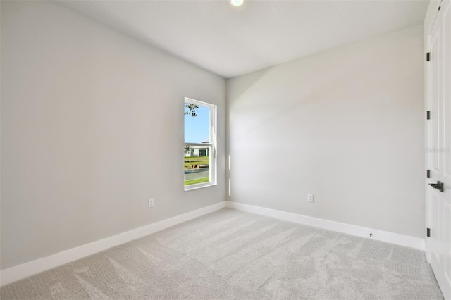 empty room featuring baseboards and light colored carpet