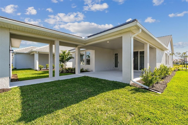back of property with stucco siding, a patio area, and a lawn
