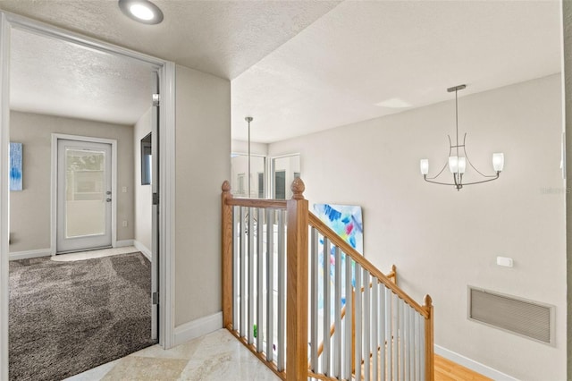 4522 W N B St, Tampa, FL 33609 - hallway with a textured ceiling, an upstairs landing, visible vents, baseboards, and an inviting chandelier