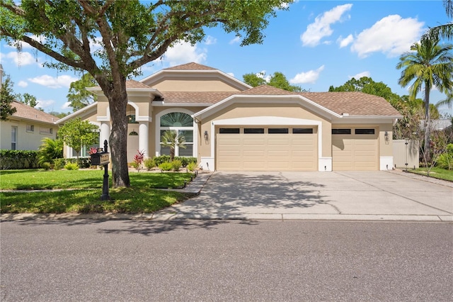 mediterranean / spanish house featuring a garage, stucco siding, a front yard, and concrete driveway