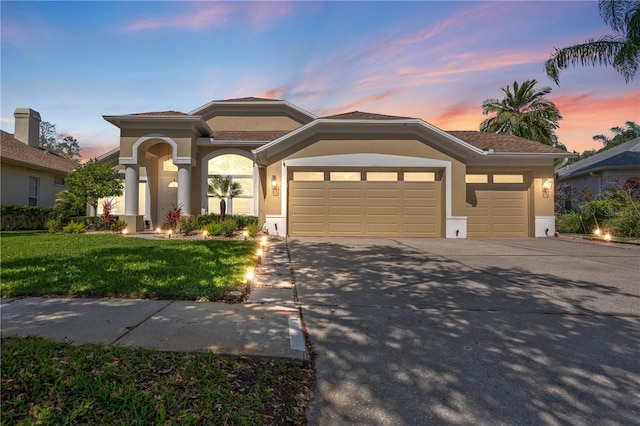 view of front facade featuring an attached garage, a lawn, stucco siding, and concrete driveway