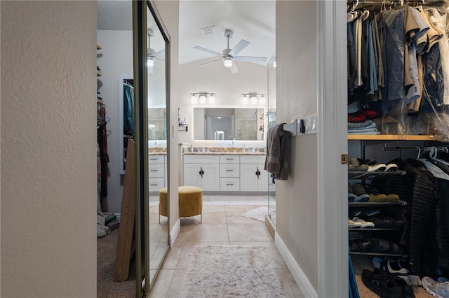 interior space featuring light tile patterned floors, ceiling fan, lofted ceiling, and visible vents