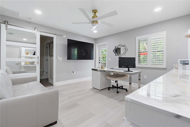 office space with baseboards, recessed lighting, a barn door, a ceiling fan, and light wood finished floors