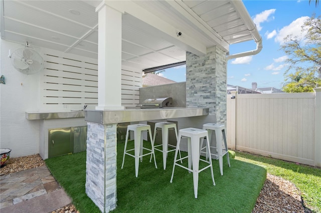 view of patio with an outdoor kitchen, fence, and outdoor wet bar