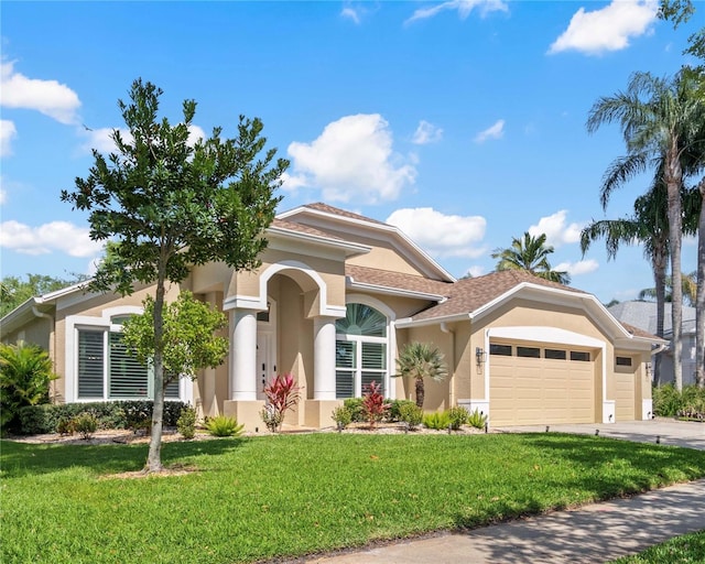 mediterranean / spanish-style home with a garage, a front lawn, stucco siding, and concrete driveway