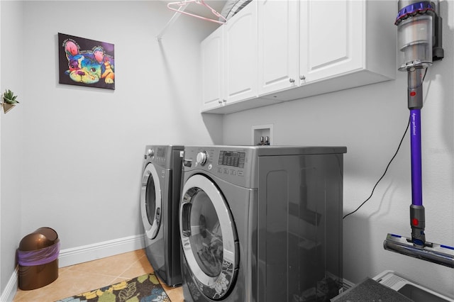 clothes washing area featuring separate washer and dryer, cabinet space, baseboards, and light tile patterned flooring