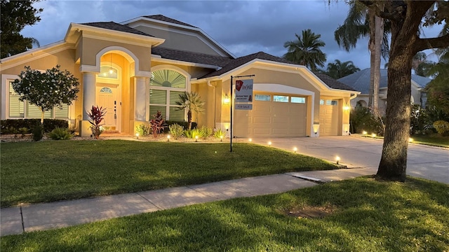 view of front of house with a garage, stucco siding, driveway, and a front lawn