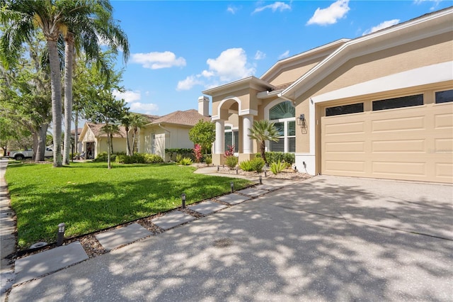 mediterranean / spanish-style home with an attached garage, a front lawn, stucco siding, and driveway